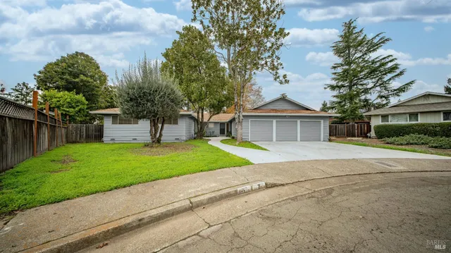 a view of house with a yard and large trees