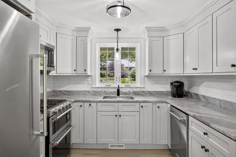 a kitchen with stainless steel appliances granite countertop a sink cabinets and a window