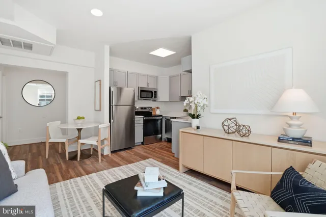 a living room with stainless steel appliances furniture a rug and a table
