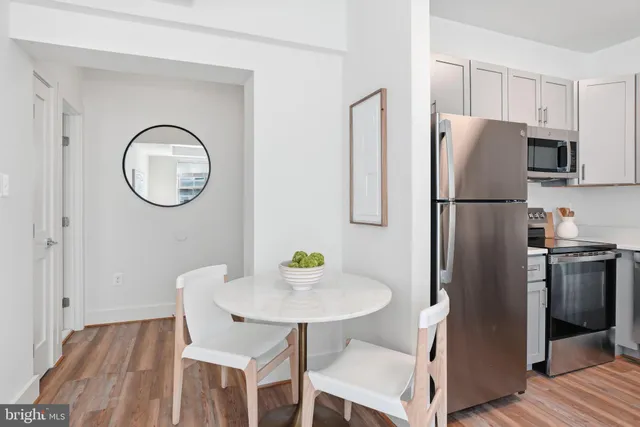 a kitchen with stainless steel appliances granite countertop a refrigerator a stove a sink and a dining table with wooden floor