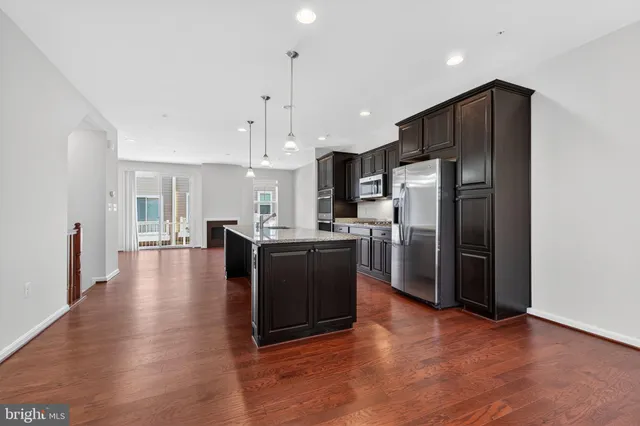 a kitchen with stainless steel appliances granite countertop a refrigerator a sink a stove a microwave and wooden floors