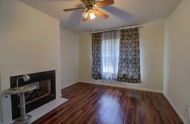 a view of an empty room with wooden floor fireplace and a window