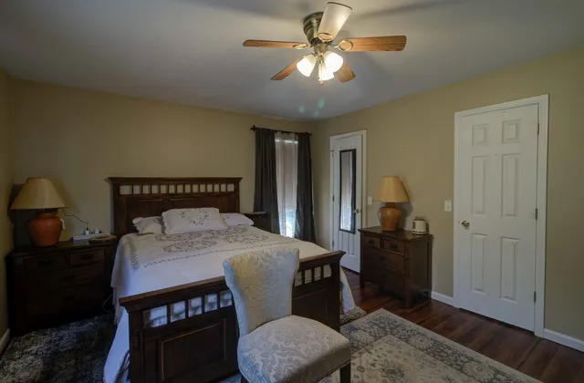 a bedroom with a bed a dresser and potted plant