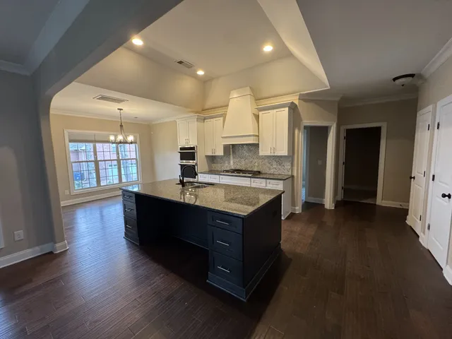an empty room with wooden floor chandelier fan and windows