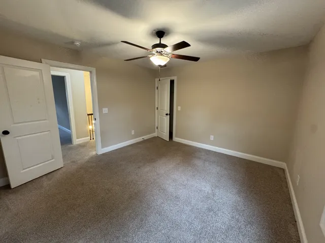 an empty room with windows and chandelier fan