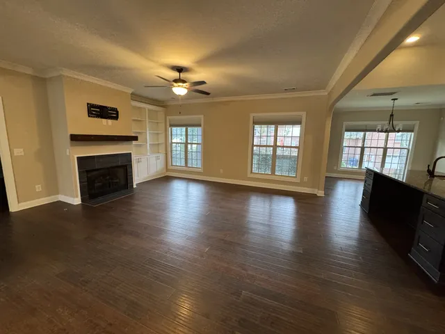 an empty room with fireplace wooden floor and windows