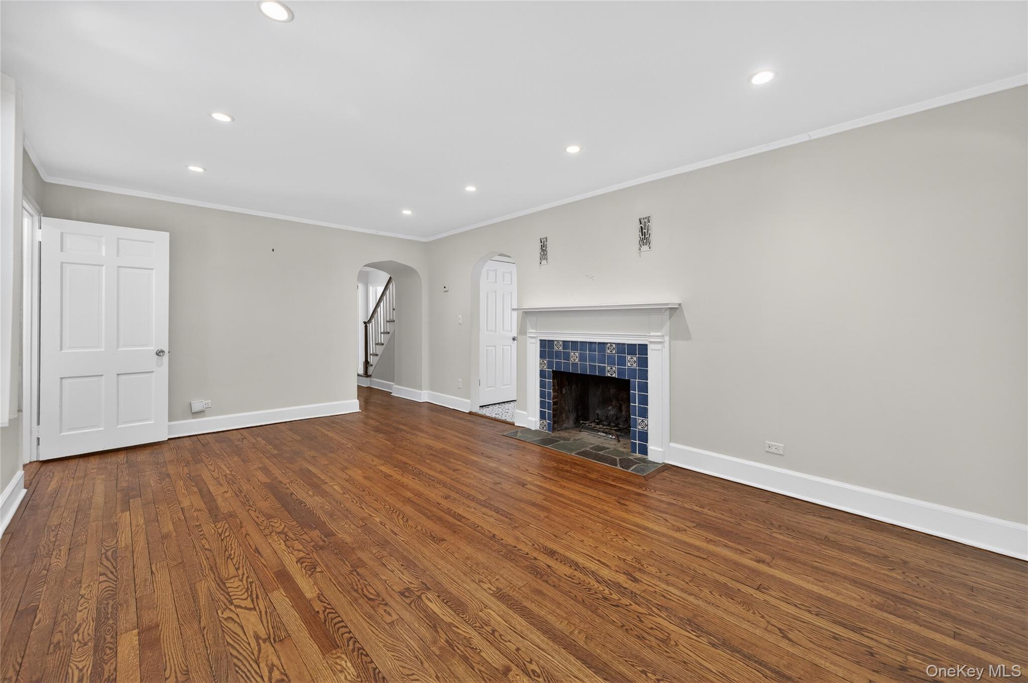 108 La Rue Drive Huntington, NY 11743 - Photo 4 of 27 Unfurnished living room featuring a fireplace, crown molding, arched walkways, dark wood finished floors, and recessed lighting