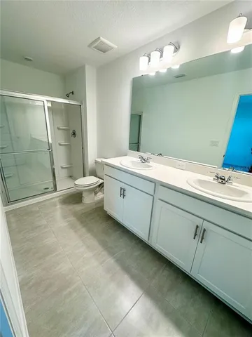 a bathroom with a double vanity sink mirror and shower