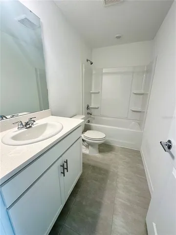 a bathroom with a granite countertop sink a toilet and bathtub