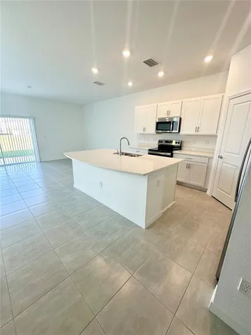 a view of kitchen with stainless steel appliances a refrigerator sink a microwave and cabinets