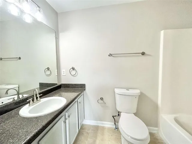 a bathroom with a granite countertop sink mirror vanity and toilet
