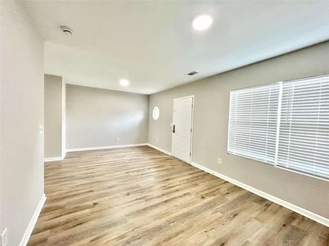 a view of an empty room with wooden floor and a window