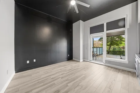 a view of an empty room with a window and wooden floor