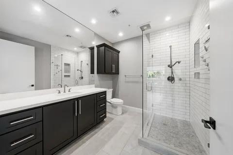 a bathroom with a double vanity sink toilet and shower