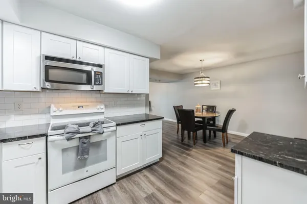 a kitchen with stainless steel appliances granite countertop a stove a microwave a sink a dining table and chairs