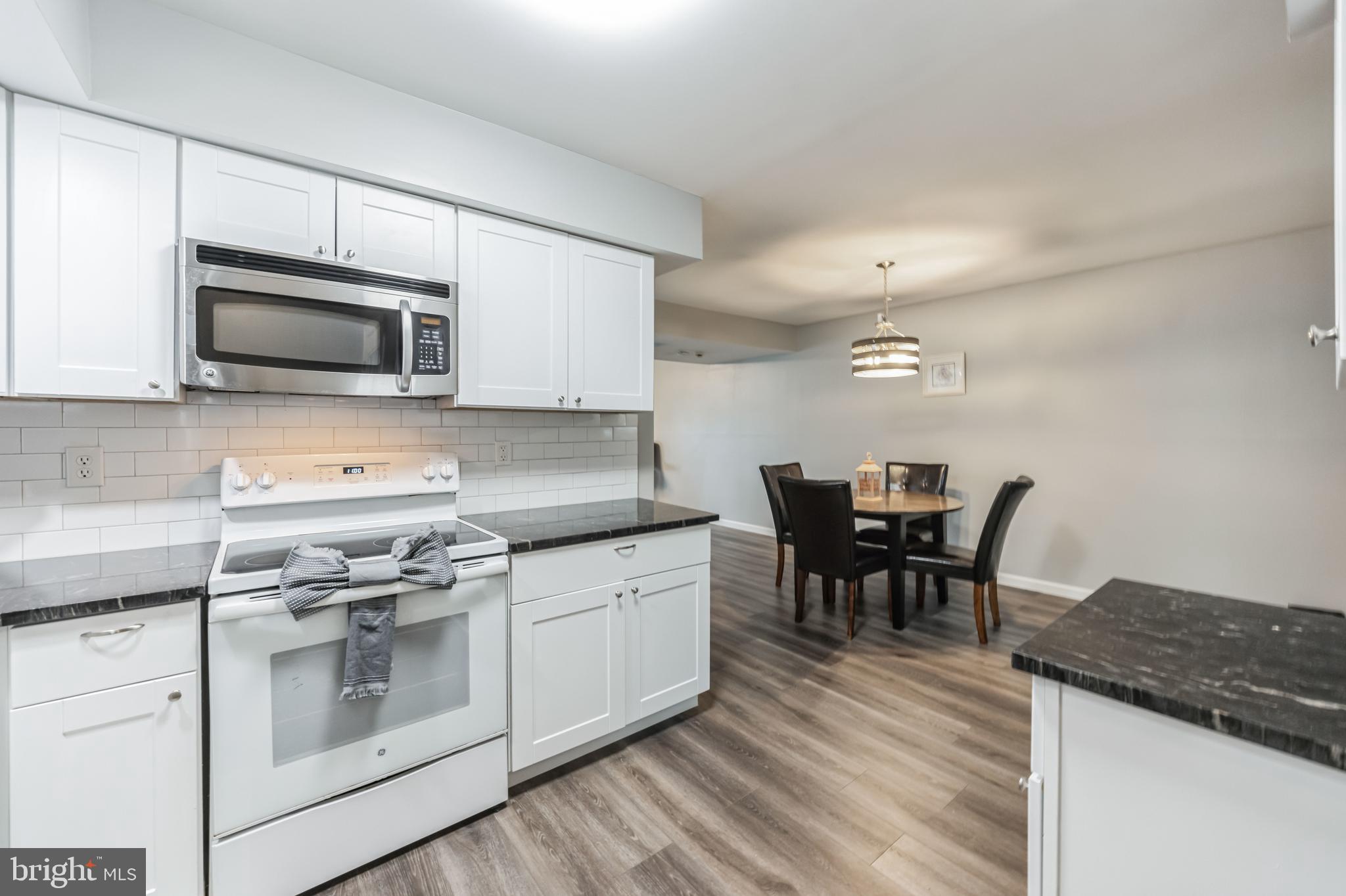 23 Raleigh Place Willingboro, NJ 08046 - Photo 13 of 27 a kitchen with stainless steel appliances granite countertop a stove a microwave a sink a dining table and chairs