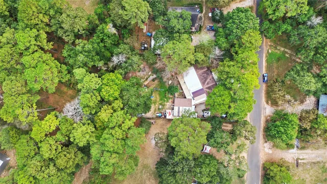 an aerial view of residential house with outdoor space and trees all around