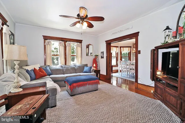 a living room with furniture a ceiling fan and a flat screen tv