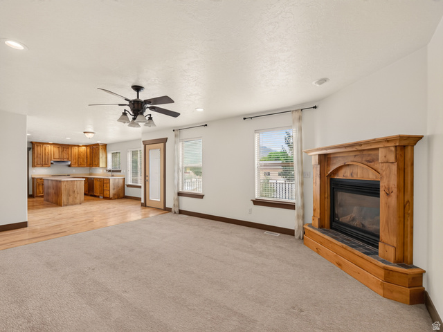 1279 West 1500th Street North Mapleton, UT 84664 - Photo 31 of 83 Open-concept living space featuring a corner fireplace with a wood mantel, overhead ceiling fan with light fixture, recessed lighting, and large windows with blinds