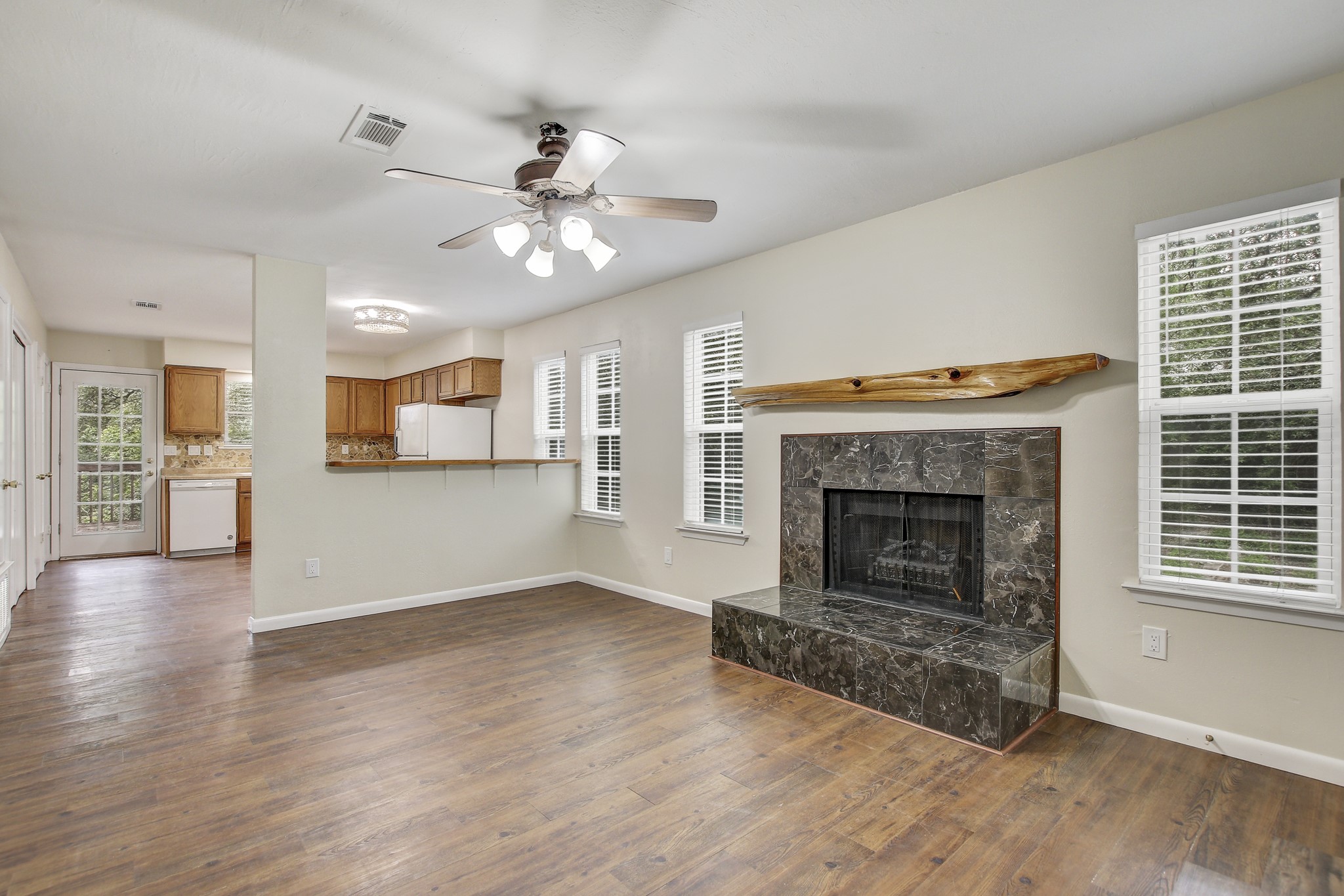 6902 Rifle Bend Austin, TX 78736 - Photo 8 of 33 a view of a livingroom with a fireplace a ceiling fan and a kitchen