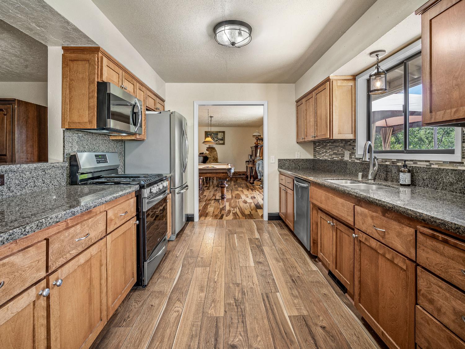 17065 Niles Road Jackson, CA 95642 - Photo 10 of 26 a large kitchen with stainless steel appliances granite countertop a stove a sink dishwasher a microwave oven and a refrigerator with wooden floor