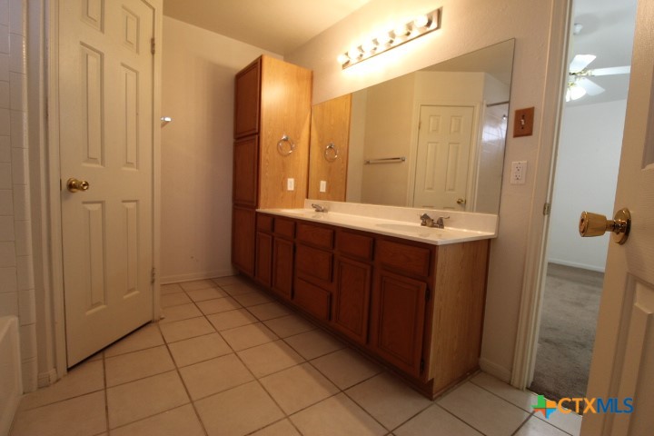 5211 James Loop Killeen, TX 76542 - Photo 12 of 18 a bathroom with a double vanity sink a mirror and a shower