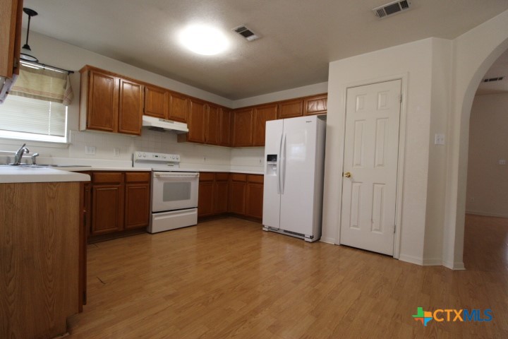 5211 James Loop Killeen, TX 76542 - Photo 4 of 18 a kitchen with stainless steel appliances granite countertop a refrigerator a sink dishwasher and wooden cabinets with wooden floor