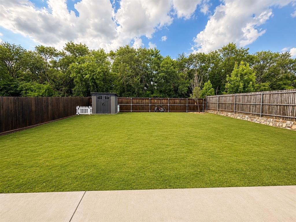 824 Juniper Street Anna, TX 75409 - Photo 22 of 25 Expansive backyard featuring a lush lawn, privacy fencing, and a built-in storage shed