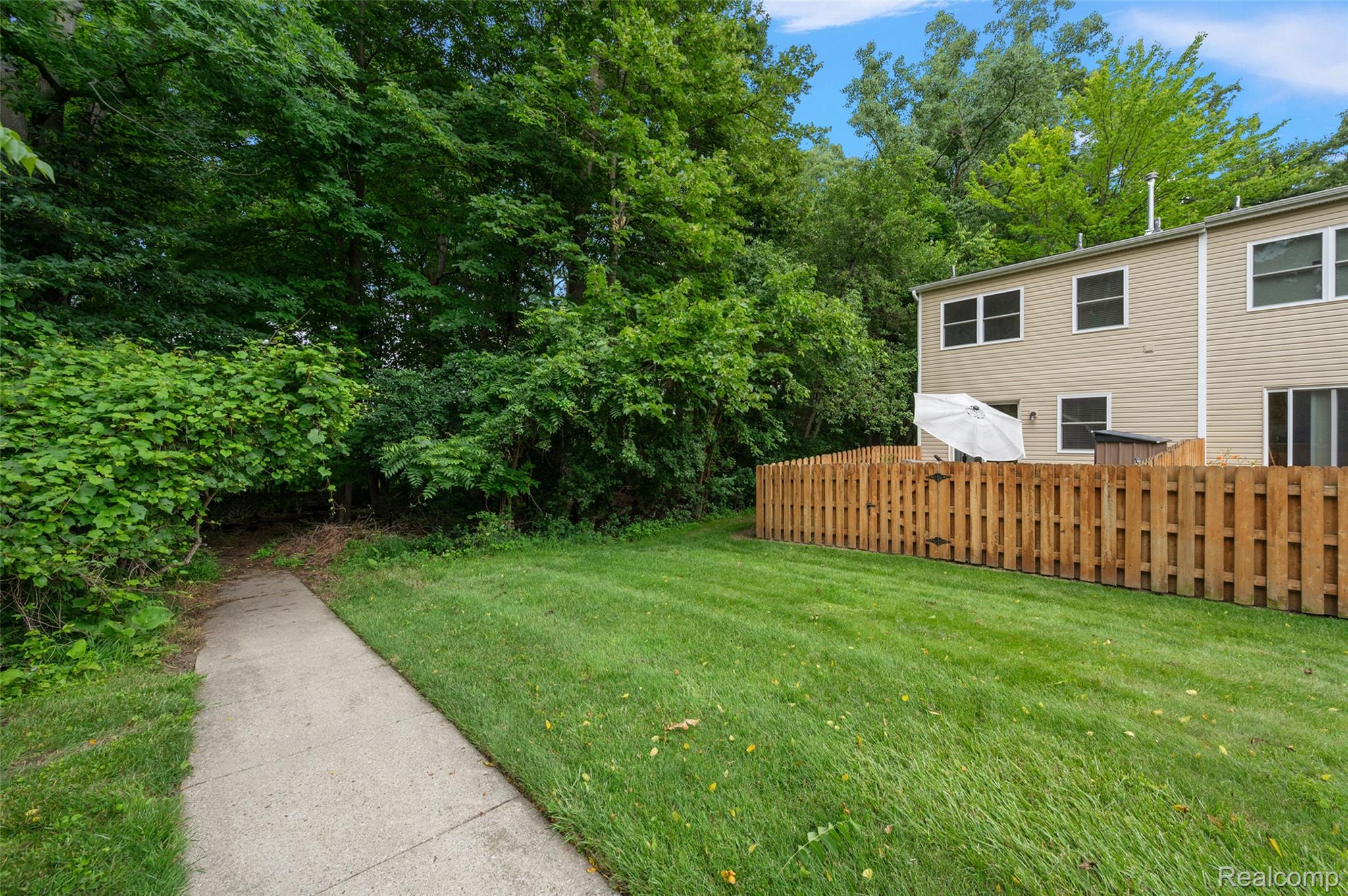 930 Little Hill Court Rochester, MI 48307 - Photo 10 of 38 Expansive green lawn bordering a concrete pathway and mature trees