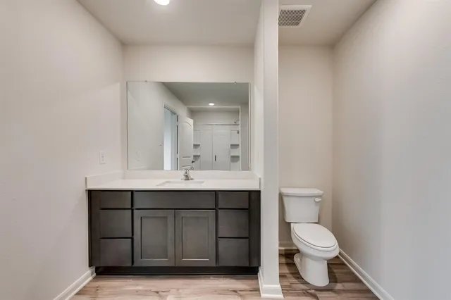 a bathroom with a toilet sink vanity and mirror