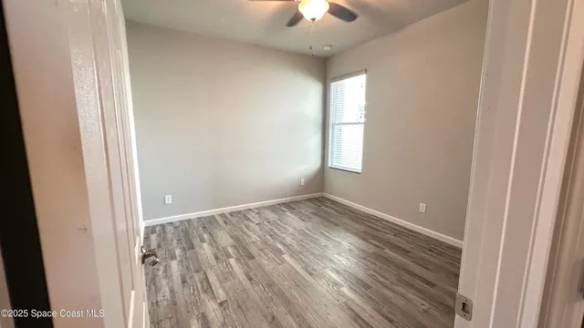 a view of an empty room with wooden floor and a window