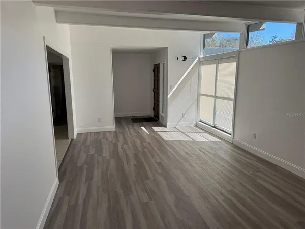 a view of an empty room with wooden floor and window