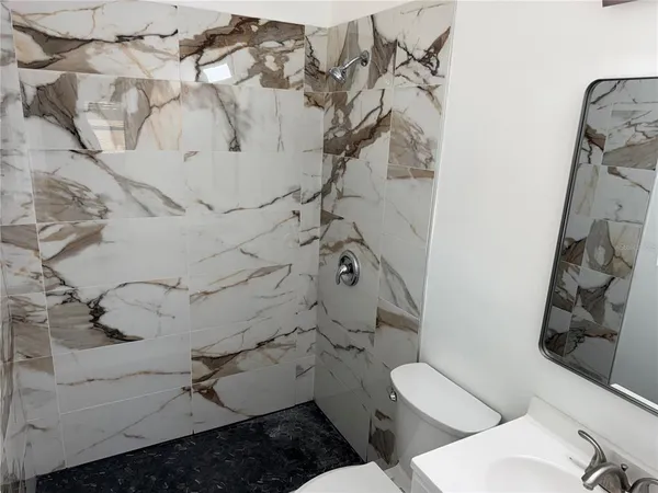 a bathroom with a toilet a sink a mirror and shower