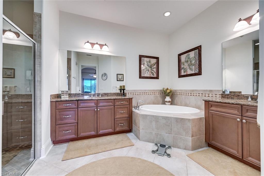 7587 Moorgate Point Way Naples, FL 34113 - Photo 38 of 50 Dual vanity with granite countertops, wood cabinetry, and extensive mirror