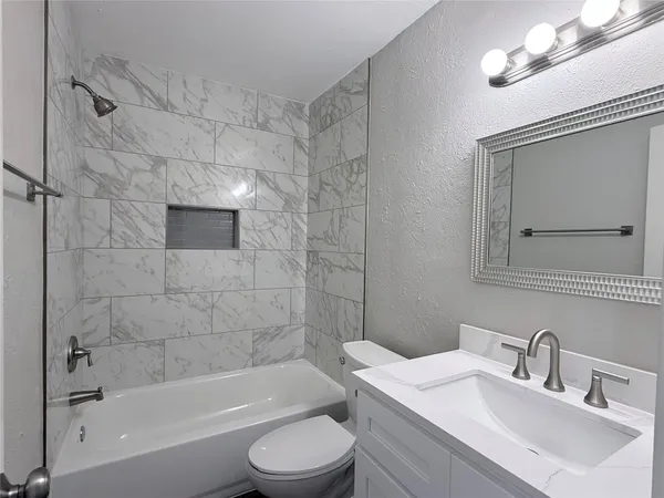 a bathroom with a bathtub shower sink vanity and toilet