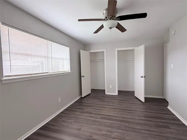 an empty room with wooden floor fan and windows