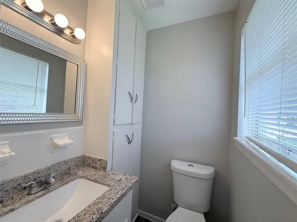 a bathroom with a granite countertop sink a toilet and bathtub