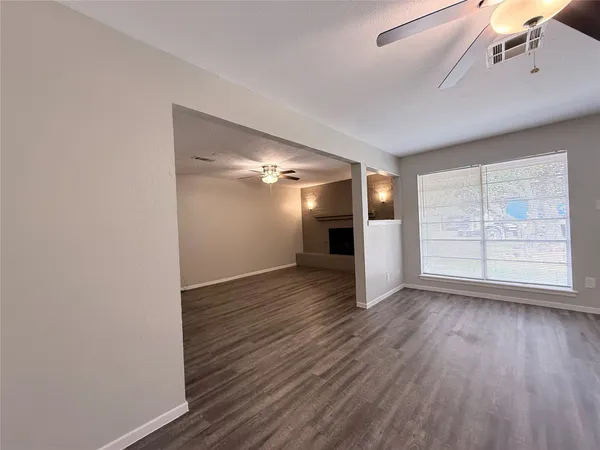 a view of an empty room with wooden floor fridge and a window