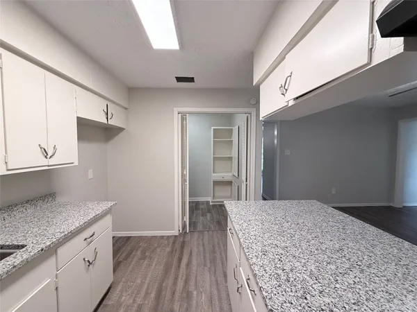 a kitchen with cabinets and wooden floor