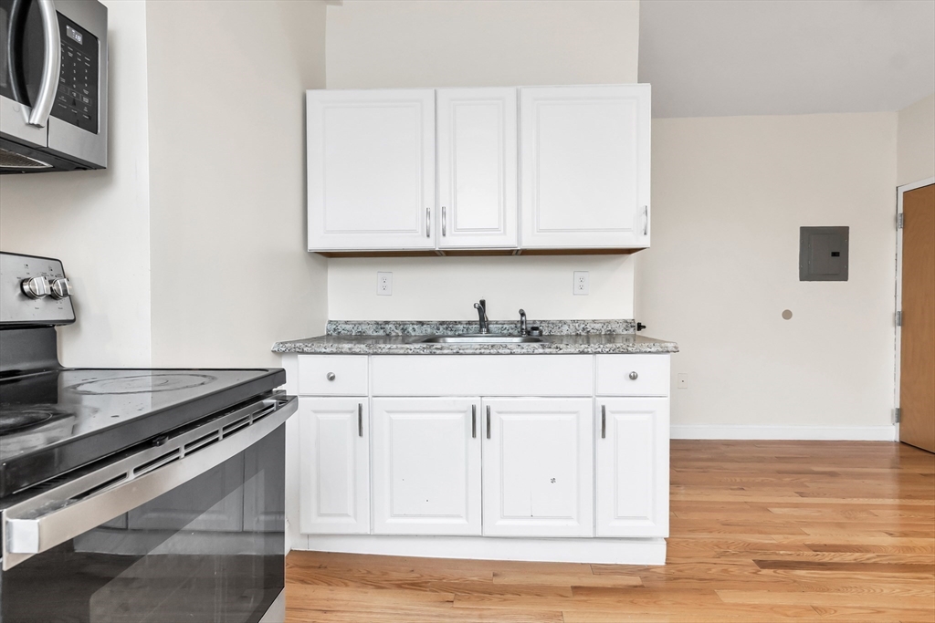 193 Appleton Street, Unit 4 Lowell, MA 01852 - Photo 15 of 21 a kitchen with granite countertop white cabinets and a stove