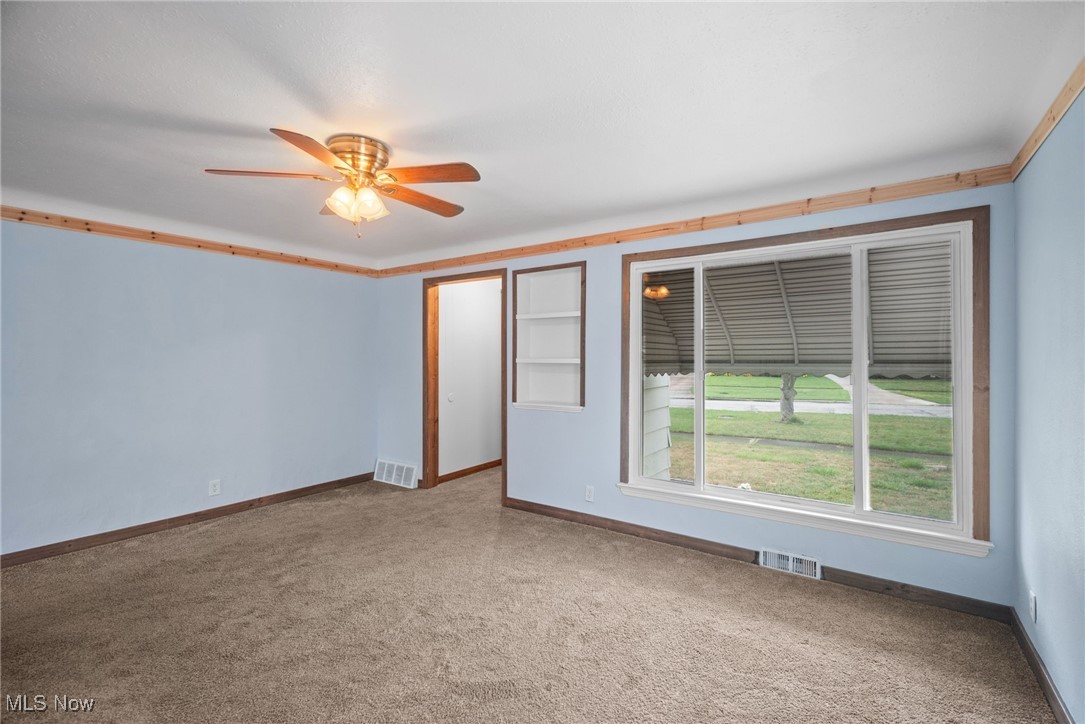 Carpeted empty room with crown molding and ceiling fan