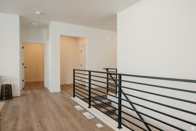 4595 North Fallow Way, Unit 511 Eagle Mountain, UT 84005 - Photo 20 of 32 Corridor featuring an upstairs landing, light wood-style floors, and a textured ceiling