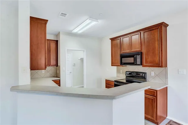 a kitchen with stainless steel appliances granite countertop a stove a sink and a microwave