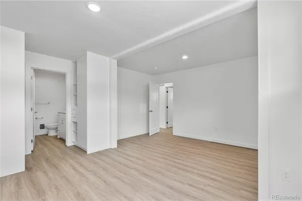 a view of an empty room with wooden floor and a bathroom