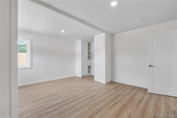 a view of an empty room with wooden floor and a window