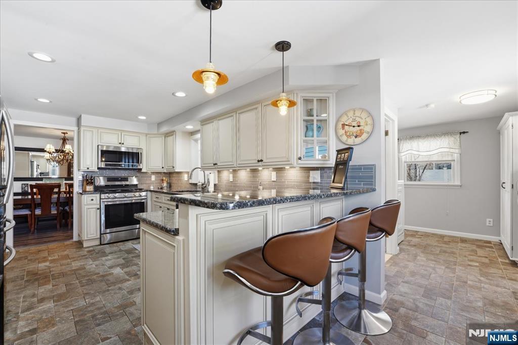 72 West Saddle River Road Waldwick, NJ 07463 - Photo 13 of 50 a kitchen with granite countertop a stove a sink a dining table and chairs