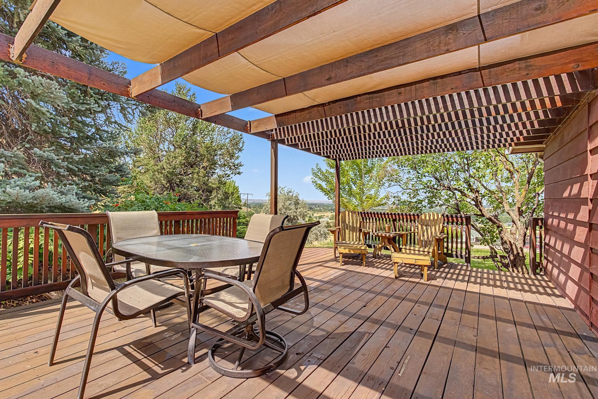 4311 Frozen Dog Road Emmett, ID 83617 - Photo 7 of 31 Expansive outdoor deck featuring wood flooring, a wood railing, and an overhead pergola with a retractable fabric shade