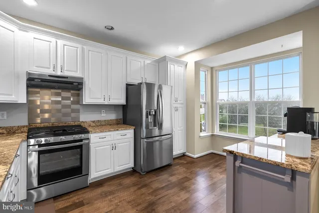 a kitchen with granite countertop a stove a sink and a refrigerator
