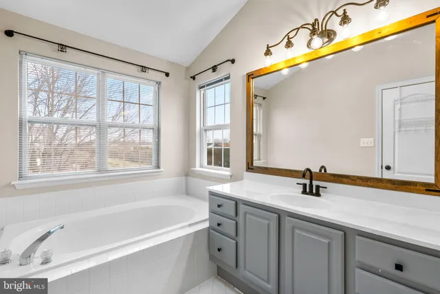 a bathroom with a tub a sink and a window
