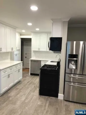 a kitchen with stainless steel appliances kitchen island granite countertop a refrigerator and a stove top oven